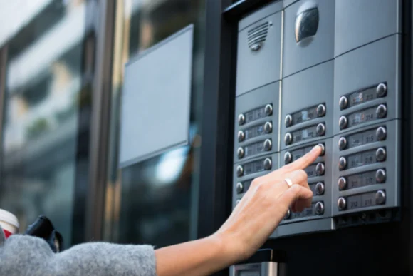 Hand drückt Klingel an Gegensprechanlage